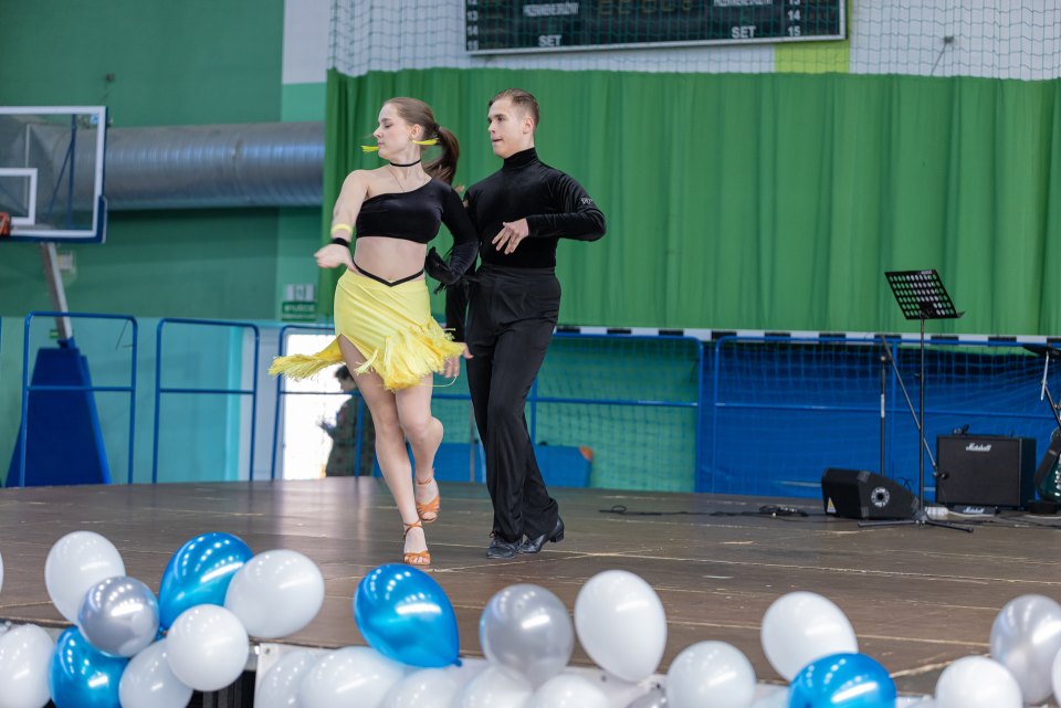 Para wykonuje figurę taneczną przed dekoracją z balonów.