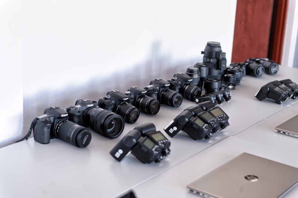 Aparaty fotograficzne i obiektywy ułożone na blacie.