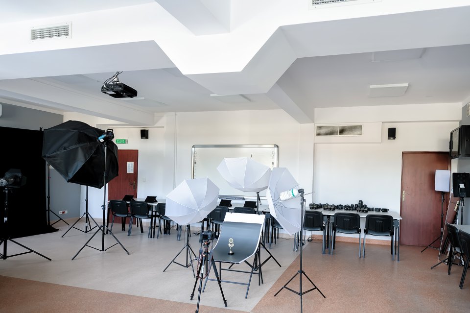 Lampy, parasole i tło fotograficzne w szkolnym studiu.