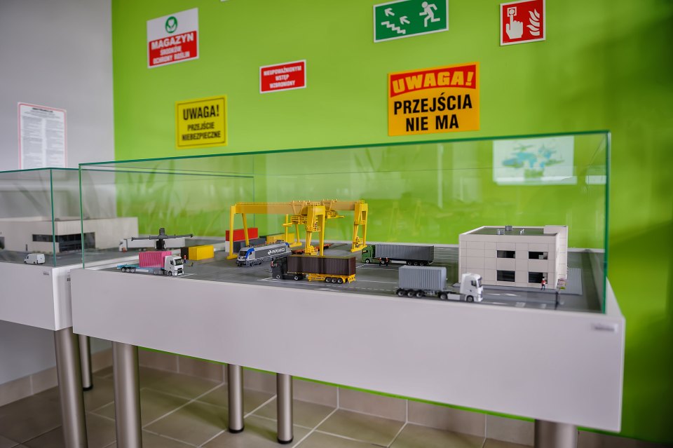 Model infrastruktury logistycznej w gablocie pod tablicami ostrzegawczymi.