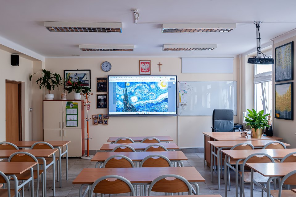 Tablica multimedialna i stanowisko nauczyciela w sali lekcyjnej.