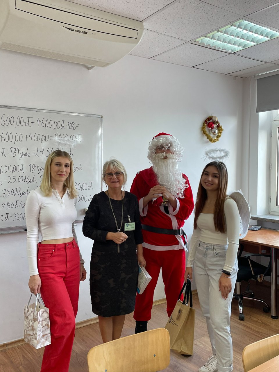 Mikołaj i pomocniczki pozują do wspólnego zdjęcia w klasie.