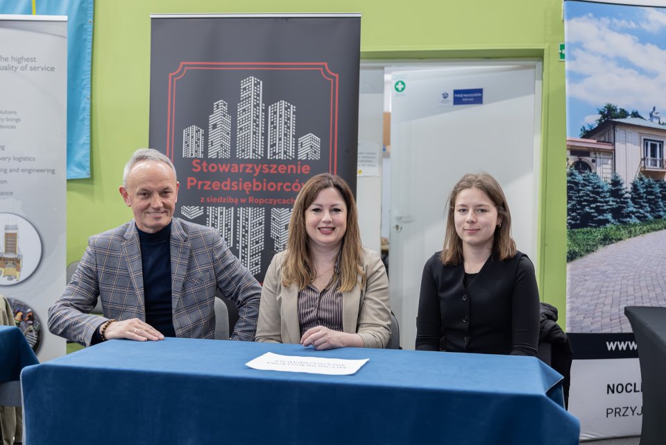 Trzy osoby przy stoisku Stowarzyszenia Przedsiębiorców podczas dni otwartych.