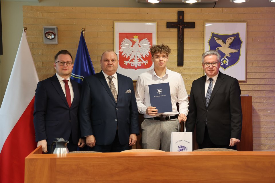 Uczestnik sesji rady pozuje z otrzymanym dokumentem.