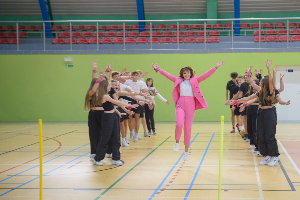 Uczestniczka przechodzi pomiędzy dwoma szeregami uczniów.