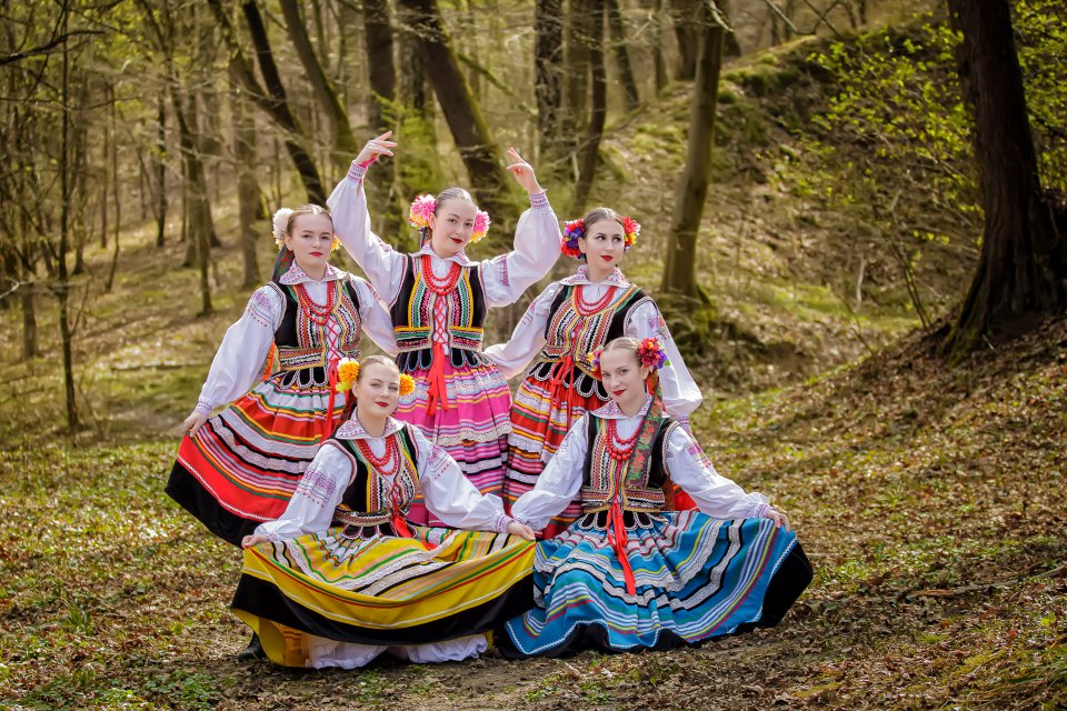 Grupa zespołu Halicz w barwnych strojach ludowych podczas sesji w lesie.