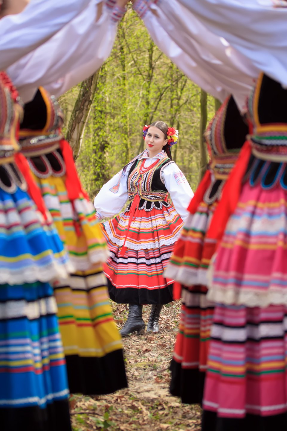 Tancerka zespołu Halicz w stroju ludowym pomiędzy pozostałymi członkami grupy.