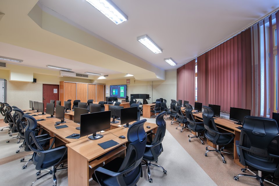 Widok rzędów stanowisk w pracowni komputerowej.