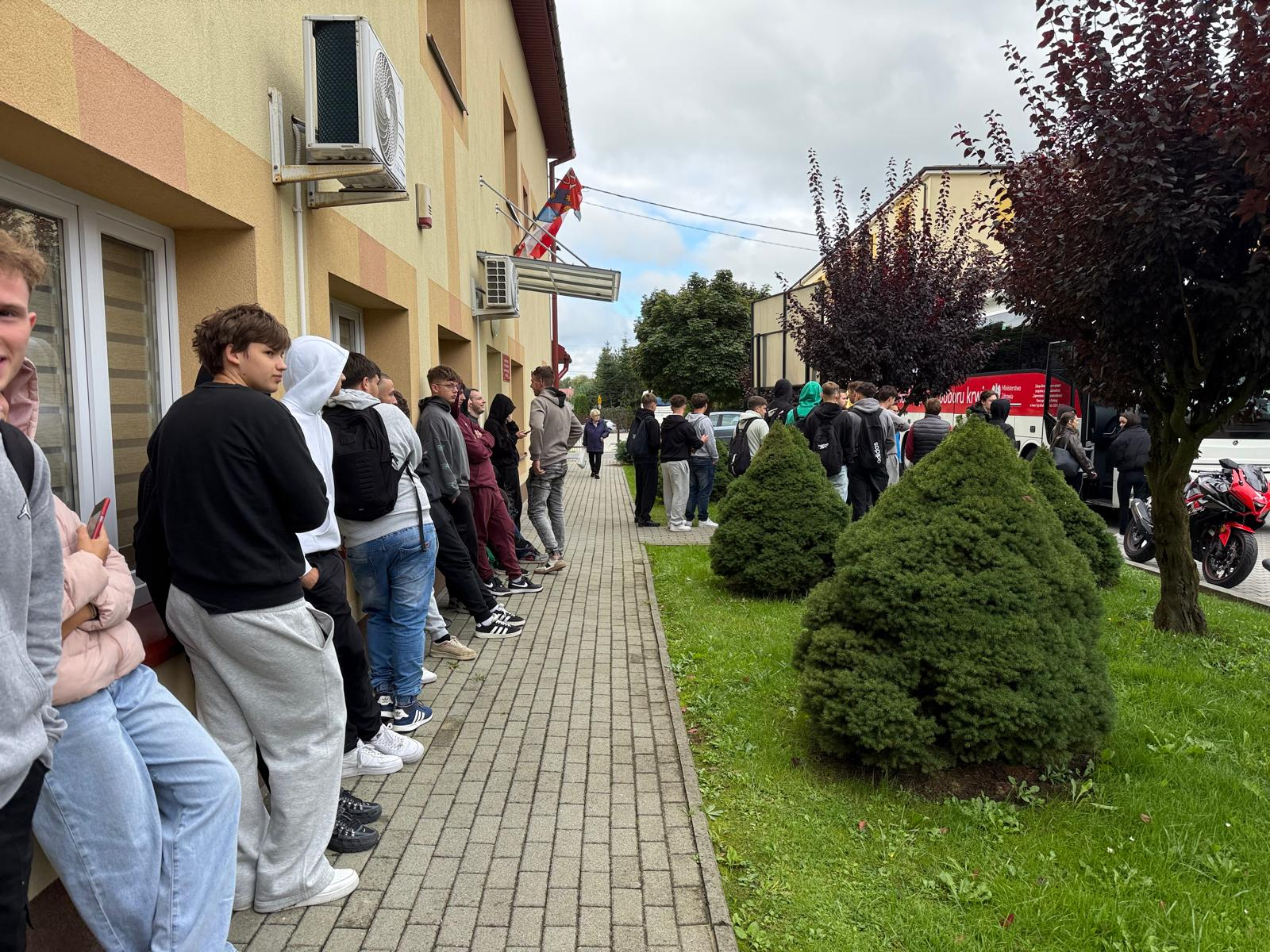 Uczestnicy akcji honorowego krwiodawstwa czekają przed budynkiem szkoły.