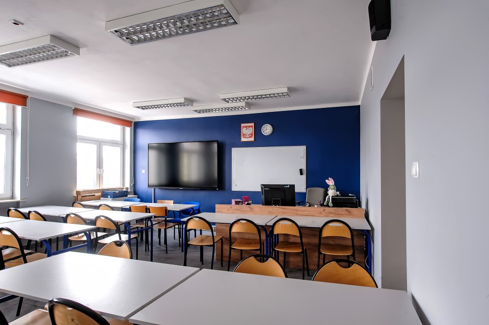 Sala z ciemnoniebieską ścianą, monitorem i białą tablicą.