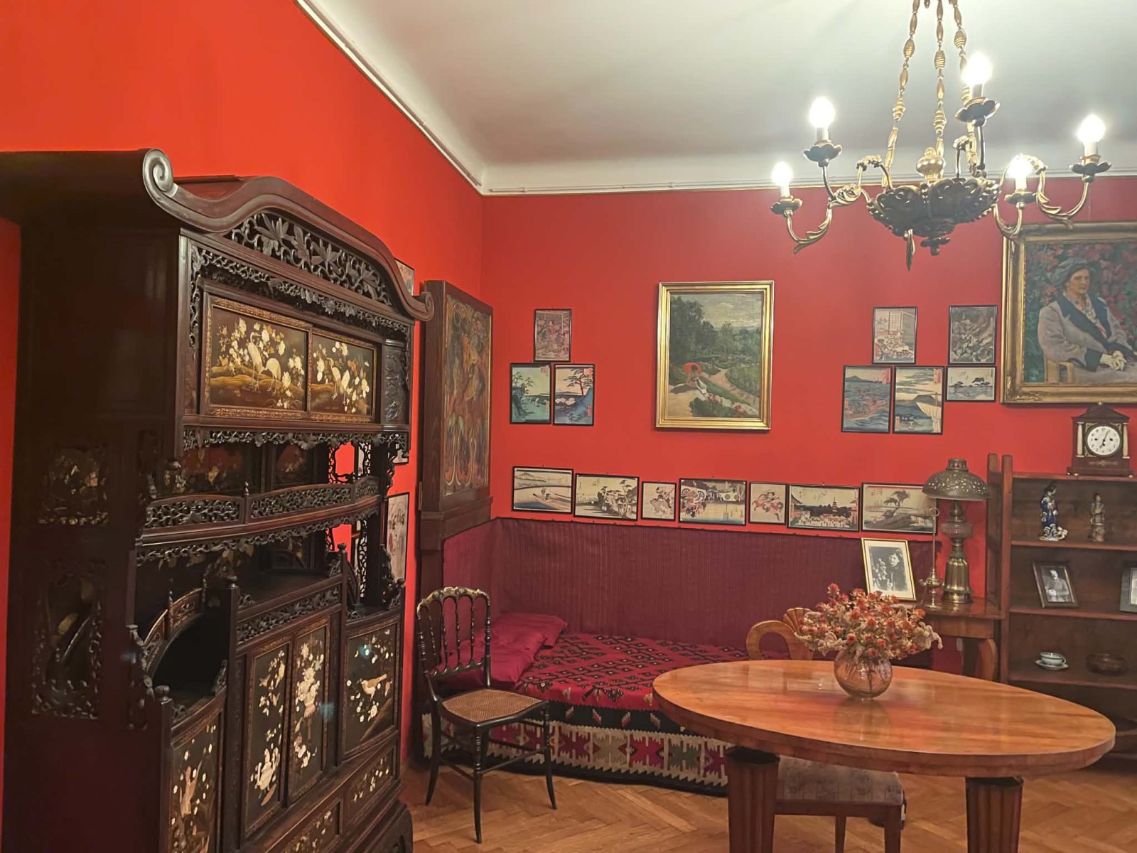 Pokój o czerwonych ścianach z obrazami i zabytkowymi meblami.