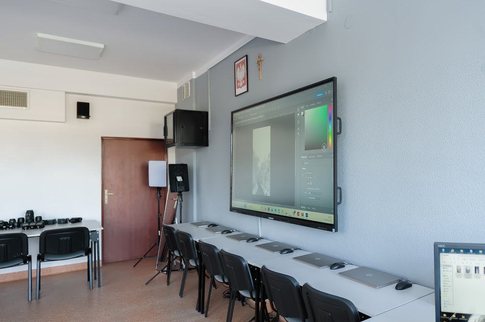 Ekran i komputery przy ścianie pracowni fotograficznej.