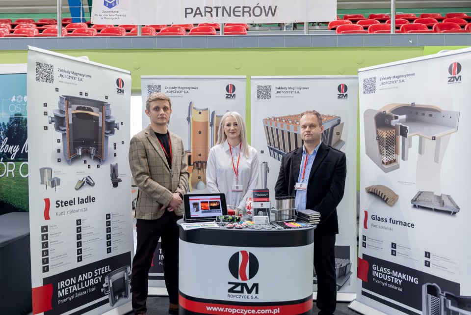 Przedstawiciele partnera szkoły przy stoisku z elementami ceramicznymi i materiałami informacyjnymi.