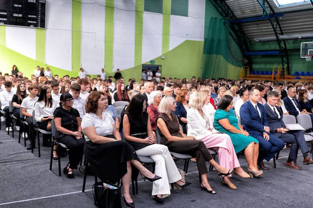Uczniowie, nauczyciele i goście zgromadzeni w hali sportowej.