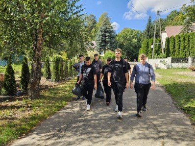 Uczniowie z workami na odpady idą osiedlową alejką.